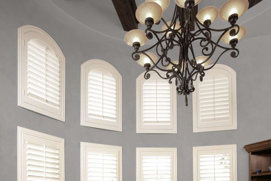 Custom interior shutters follow the curved lines of your arched window to highlight--not hide--its beauty. Polywood shutters on several small arched windows