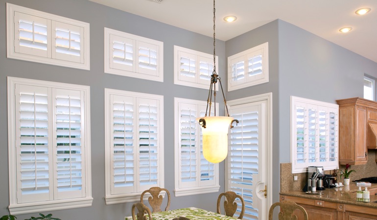 Plantation shutters can resolve both sun glare and heat loss problems. White plantation shutters in kitchen